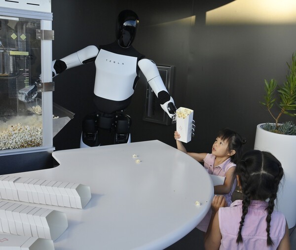 21일 테슬라 '다이너'에서 로봇 '옵티머스'가 어린이에게 팝콘을 건네는 모습.  사진=UPI, 연합뉴스